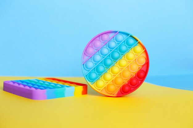 Фото Современная модная силиконовая игрушка появляется на разноцветном фоне. детская развивающая игрушка-антистресс