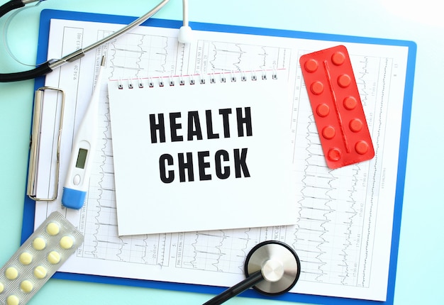 사진 health check라는 텍스트가 있는 메모장은 파란색 배경에 청진기와 알약이 있는 의료 클립보드에 있습니다.