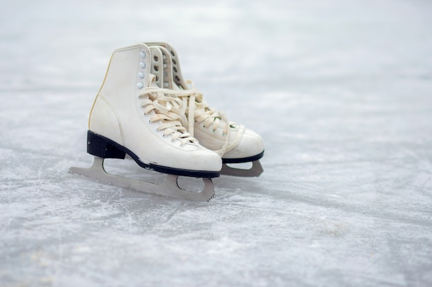 사진 한 쌍의 화이트 피겨 스케이트가 열린 아이스 링크에 서 있습니다. 겨울 스포츠