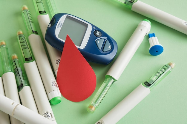 Фото Бумажная капля крови и много шприц-ручек с инсулином