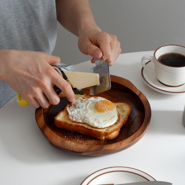Фото Человек режет кусок хлеба с яйцом на нем