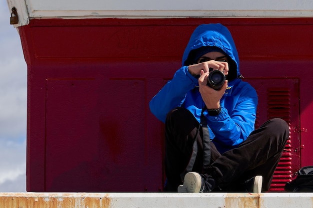 写真 赤いトラックをカメラで撮影する人。