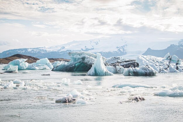 写真 氷山と山を背景にした凍った湖の写真。