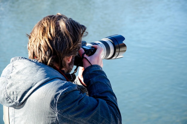 写真 カメラを持った写真家が写真を撮る 仕事中のパパラッチ カメラを持った若い男性