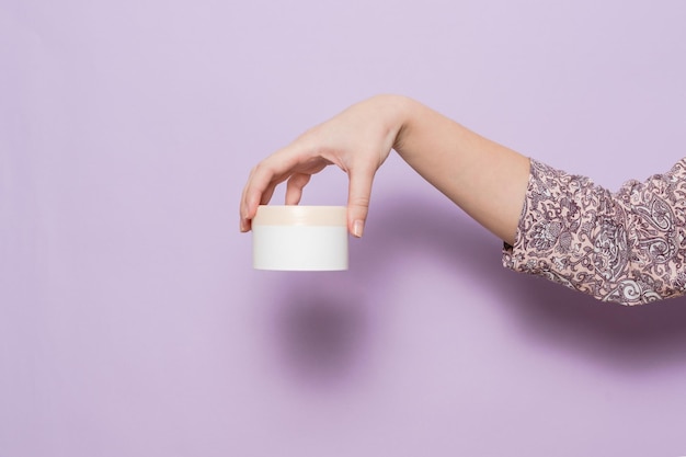 Фото Пластиковая банка-контейнер для крема в женской руке косметический продукт