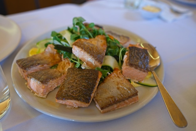 사진 측면에 포크가 있는 연어와 샐러드 한 접시