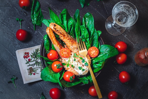 Фото Тарелка со свежим зеленым сырым шпинатом и жареными помидорами из дикого лосося и соусом из сливочного сыра
