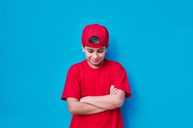 目を閉じて見下ろしている赤い帽子とtシャツの怒っている少年の肖像画