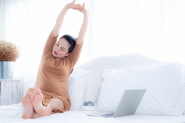 写真 妊娠中の女性は、コンピューターを使用した後、手を上げてリラックスします。健康な妊娠の概念。