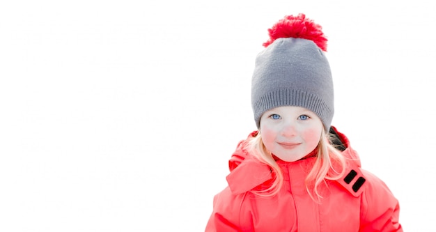 笑みを浮かべて、雪の中で笑っているニットの冬の帽子とピンクのジャンプスーツで、かなり白い女の子