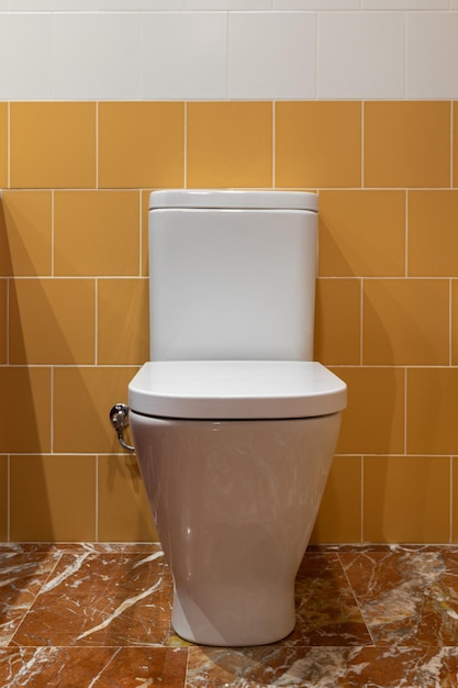 Фото Чистый белый туалет на фоне оранжевых и белых плиток и мраморного пола