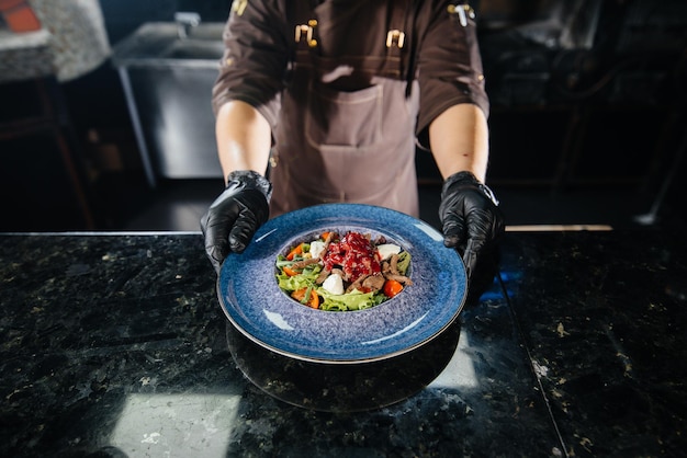 Фото Профессиональный повар подает свежеприготовленный салат из помидоров и телятины с соусом в ресторане изысканной кухни крупным планом.