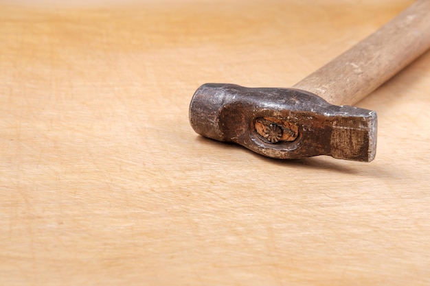 Фото Ржавый молоток с повреждениями и деревянной ручкой лежит на светлой доске