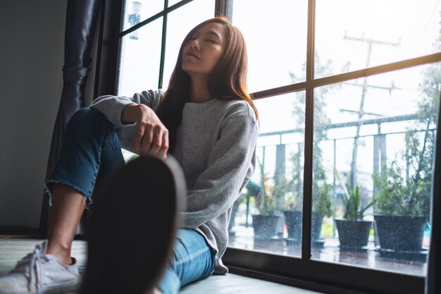 사진 슬프고 스트레스를 받는 젊은 아시아 여성이 방에서 혼자 앉아 있습니다.