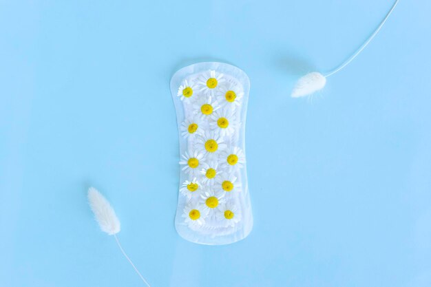 Фото Санитарная подушка с ромашковыми цветами лежит на желтом фоне менструации