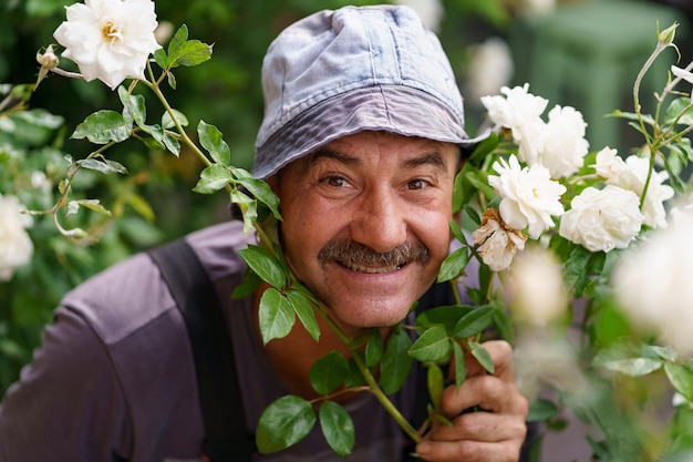 写真 口ひげを持つ年配の屈託のない男がバラの茂みに立って、笑顔の大きな肖像画