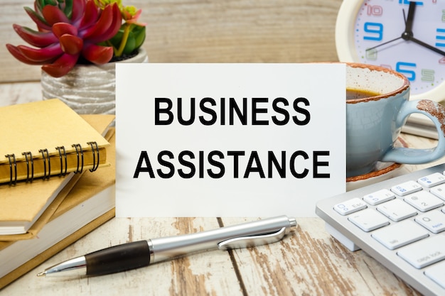 写真 事務用品のあるテーブルに「businessassistance」と書かれた看板