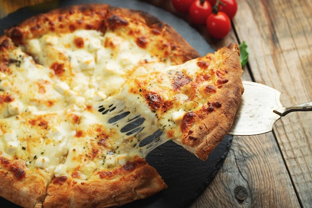 写真 ストレッチ チーズをのせた熱々のイタリアン ピザのスライス バジルを添えた 4 種類のチーズのピザ