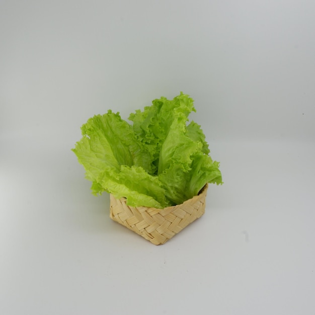 Фото Маленькая корзинка с салатом на белом фоне