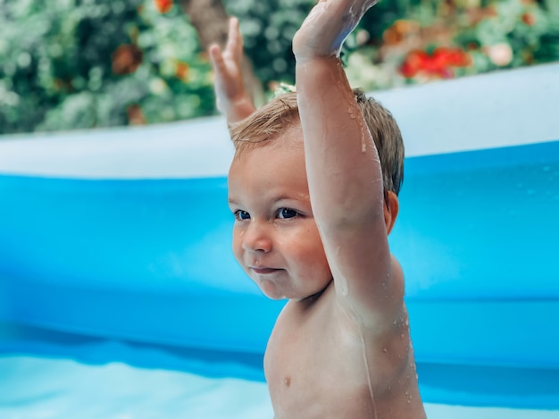 晴れた夏の天候のインフレータブルキッズラウンドプールの小さな子供。夏と休暇のコンセプト。