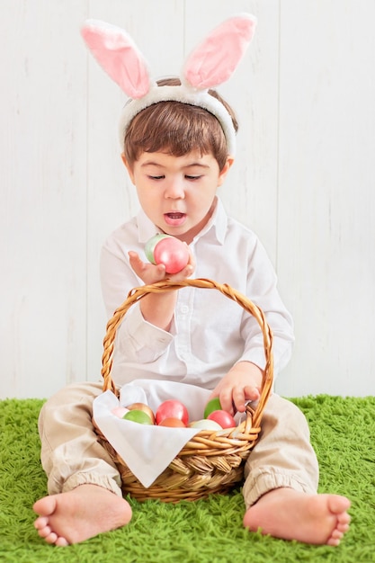사진 토끼 귀에 작은 아이는 색깔 계란 바구니와 함께 바닥에 앉아