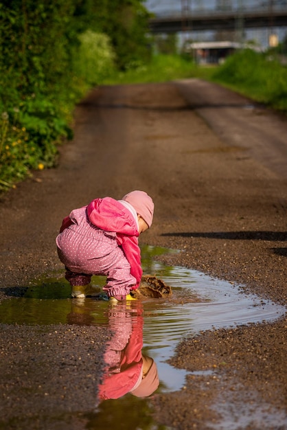 写真 小さな子供が雨の池で遊んでいます