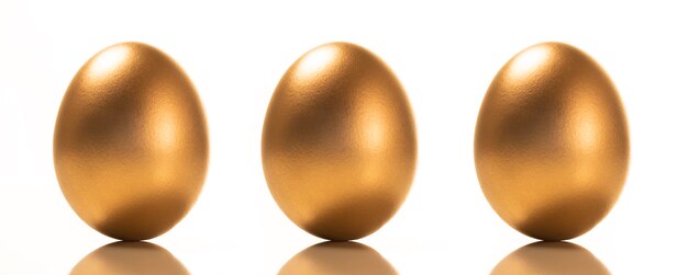 Фото Небольшая группа золотых яиц на белом фоне.