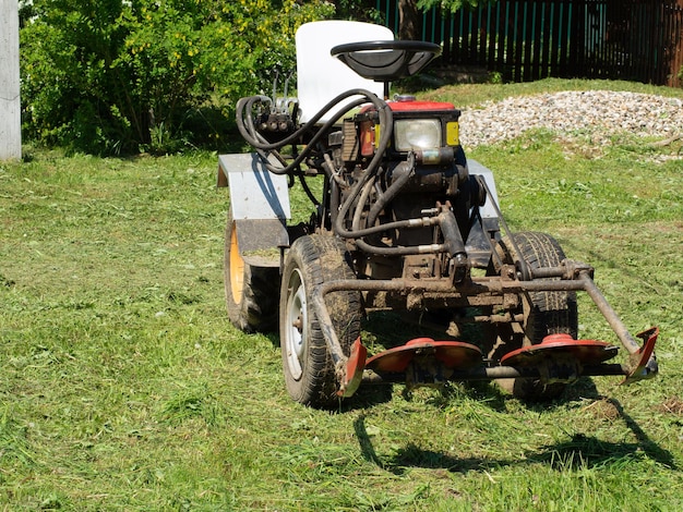 写真 農業機械の上に立つ草用の芝刈り機付きの小型トラクター