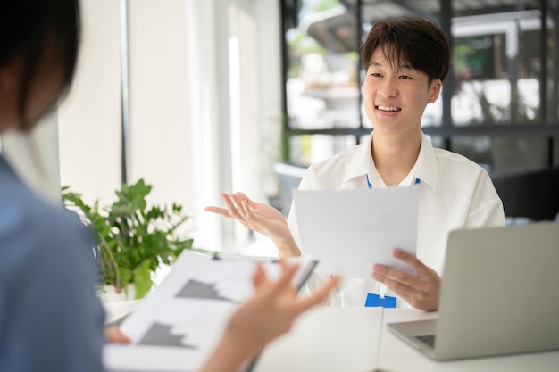 写真 賢いアジア人の男性会社員が同僚と仕事について話し合っている