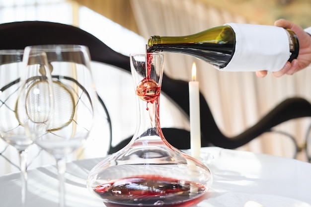 Фото Сомелье наливает красное вино в графин