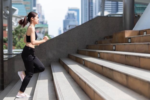 写真 屋外の階段を駆け上がる体操服を着た東南アジアの女性。