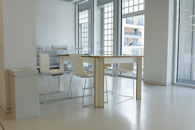 Фото Просторный офис с большими окнами и белыми стенами минималистический офисный интерьер