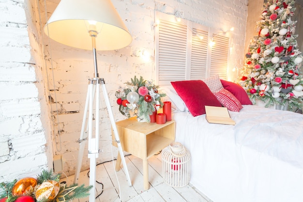写真 装飾されたクリスマスツリーと花輪を備えたロフトスタイルの広々とした白い光のベッドルーム。