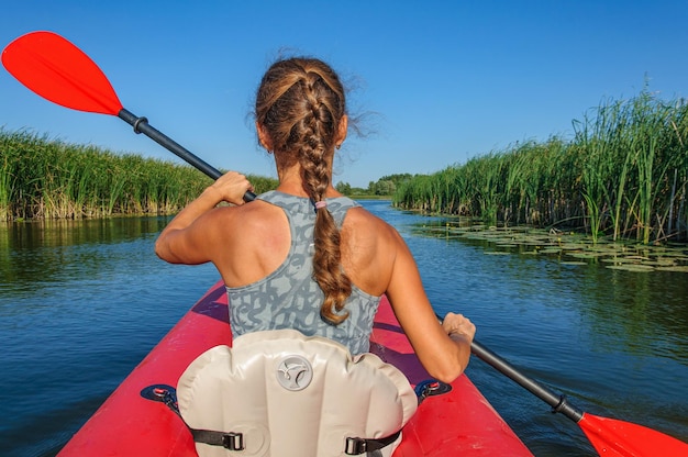 Фото Спортивная девушка на красном каяке плывет по реке здвиж. украина