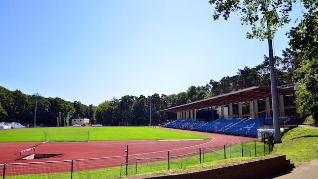 사진 배경에 빨간색 트랙과 나무가 있는 파란색 경기장이 있는 경기장.
