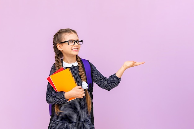 안경을 쓴 한 학생이 학생을 위한 코스를 손에 들고 있는 분홍색 배경에 당신의 광고를 들고 있습니다