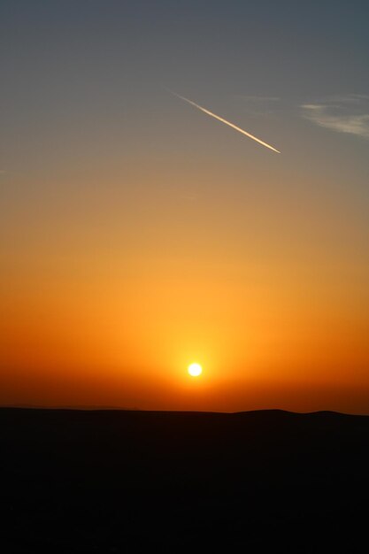 写真 太陽が背景で空に沈んでいます