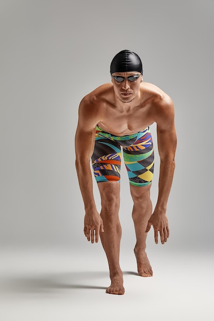 Фото Пловец в плавках готовится к старту спортсмен на сером фоне готовится к заплыву я принимаю позу для заплыва в бассейне в очках и маске