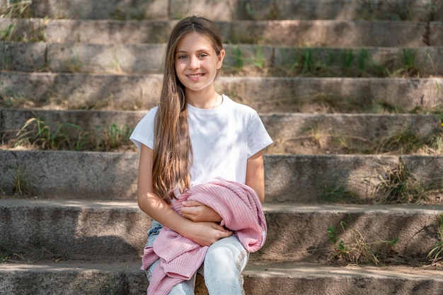 写真 ジーンズの 10 代の少女が通りの階段の階段に座っています。