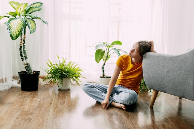 写真 思いやりのある女の子が部屋の床に座って遠くを見ています