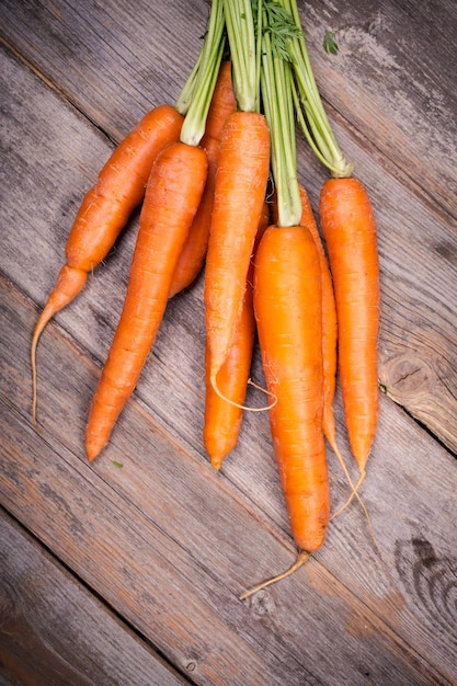 Фото Связанная связка свежей моркови на старом деревянном фоне