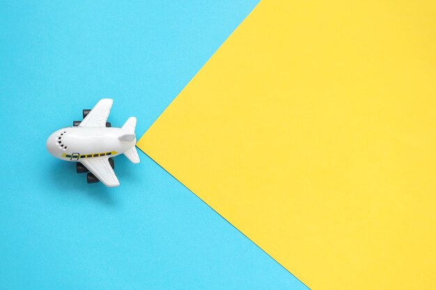 Фото Игрушечный самолетик летит на желто-синем фоне пустое место для вставки текста