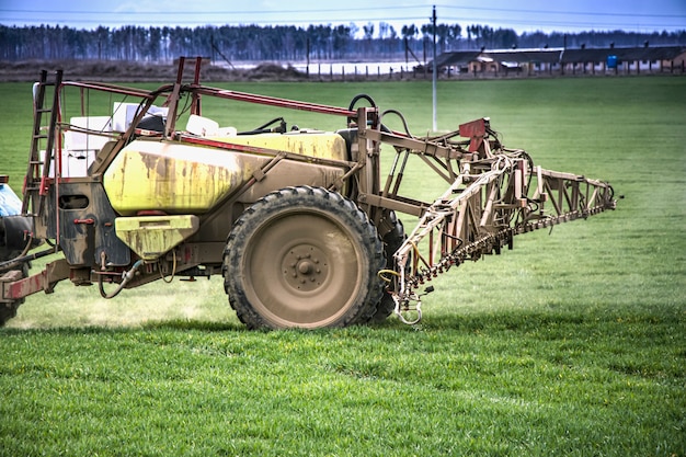 Фото Трактор опрыскивает поле добавками для выращивания растений и уничтожает болезни растений. сельское хозяйство. предоставление еды.