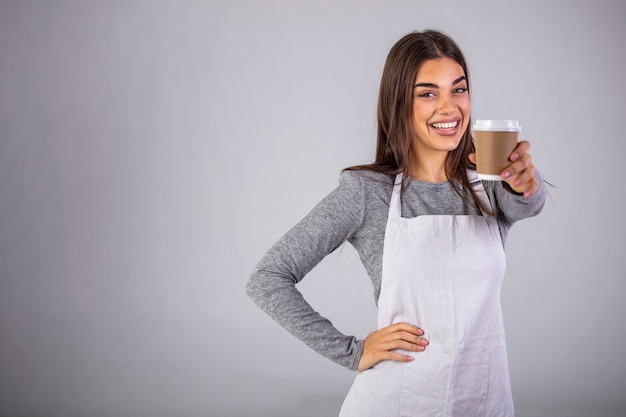 Фото Официантка держит и подает бумажный стаканчик горячего кофе на сером
