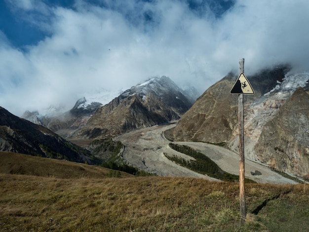 写真 美しい山を背景に山から落下する可能性のある警告サイン