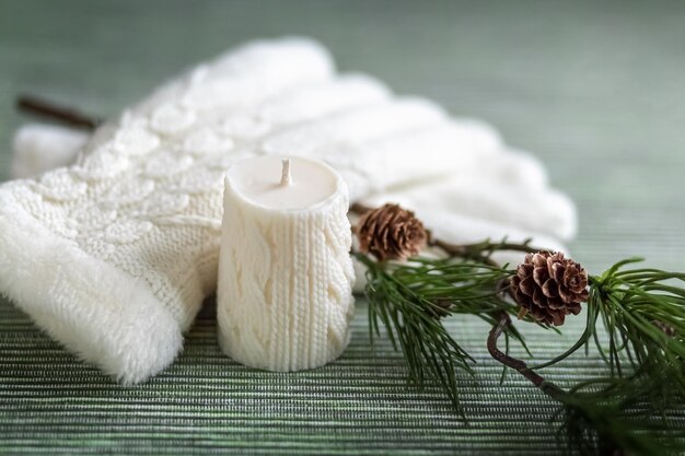 사진 니트 패턴이 있는 흰색 양초 흰색 니트 장갑과 콘 카드가 있는 소나무 가지