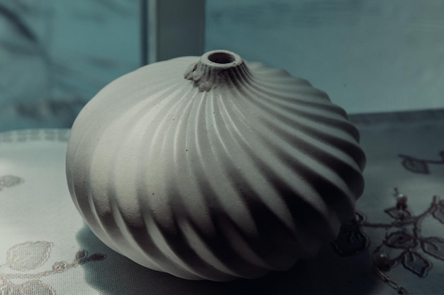 Фото Белая керамическая ваза с изображением гребешка.