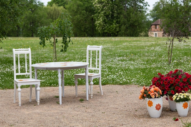 사진 백색 테이블 과 두 개의 빈티지 의자 가 결혼식 을 위해 공원 에 서 있다