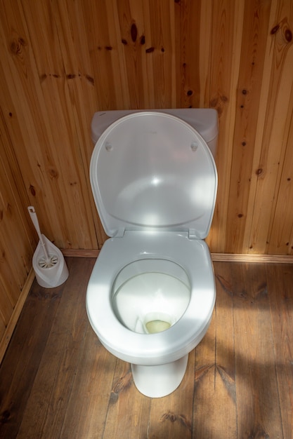 写真 シンプルな実生活の素朴な木製トイレトイレコンセプトのプラスチック蓋付きの白いトイレ