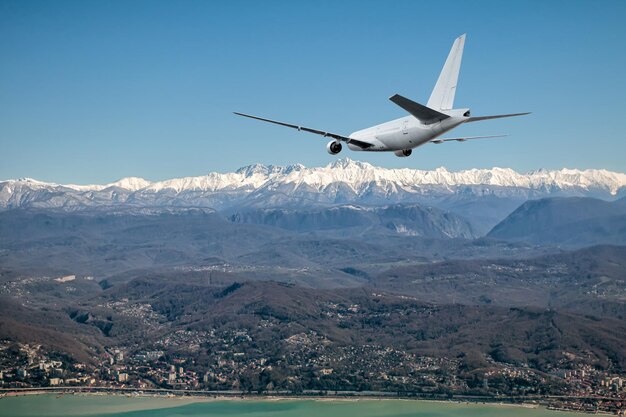 写真 海岸のリゾートの山の町で白い幅広い乗客機が接近している